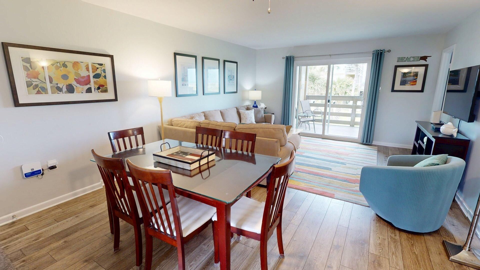 A modern living room with a dining area, a sofa set, a blue armchair, and a balcony with a view.