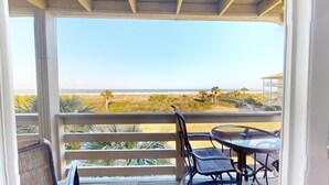 A balcony with a view of the beach, a table, and chairs. - Lighthouse Point 3 by Tybee Vacation Rentals (Tybee Island)