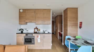 A modern kitchen with wooden cabinets, a built-in oven, and a dining area with a table and chairs.