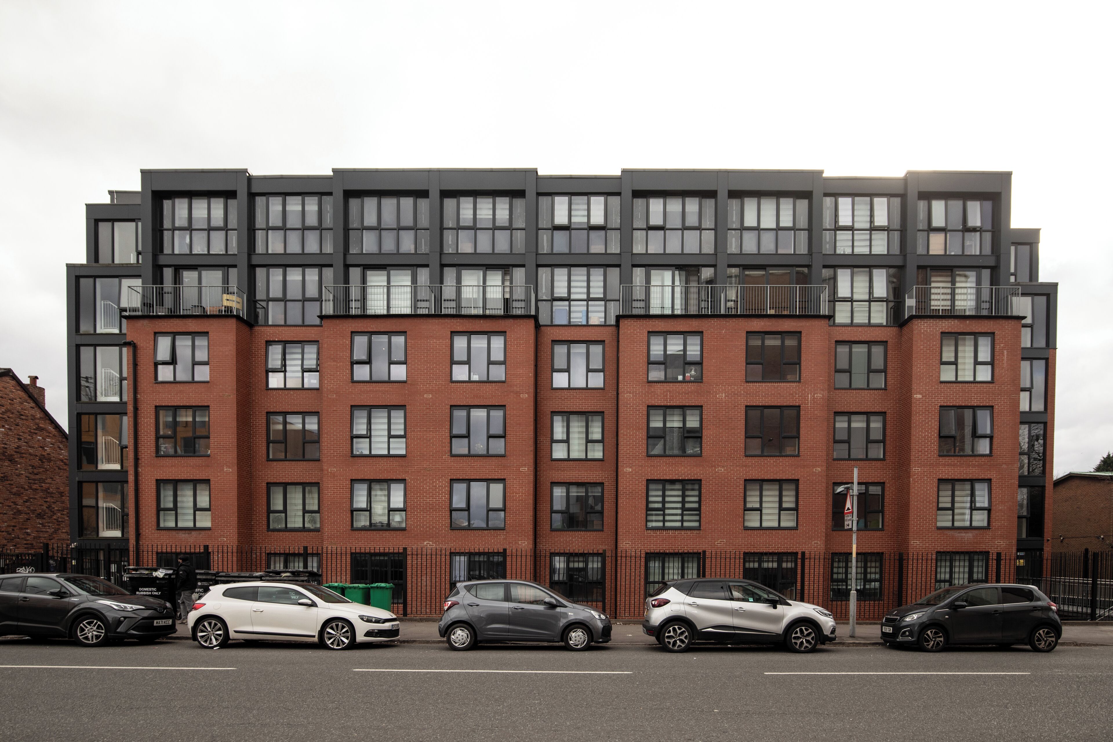 Un immeuble résidentiel à plusieurs étages, doté d’une façade en briques et de grandes fenêtres.