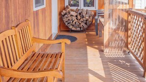 A wooden porch with a bench, a stack of firewood, and a view of a forested area. - Minutes from SLU, Clarkson, & SUNY schools.  4-bd Family Friendly Farmhouse (Canton)