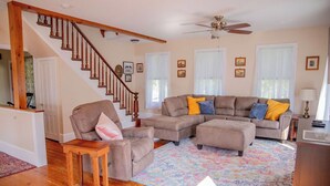 A living room with a wooden staircase, a sectional sofa, and a patterned rug. - Minutes from SLU, Clarkson, & SUNY schools.  4-bd Family Friendly Farmhouse (Canton)