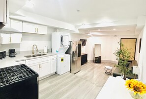 Eine moderne Küche mit weißen Schränken, einer eingebauten Mikrowelle, einer Kaffeemaschine und einem Kühlschrank.