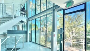 A modern building with a glass facade, a staircase, and a clear view of the outdoors. - Charming Glass-Front One Bedroom Spacious Living Free Parking (Los Angeles)
