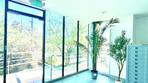 A spacious lobby with large windows, a potted plant, and a metal filing cabinet. - Charming Glass-Front One Bedroom Spacious Living Free Parking (Los Angeles)
