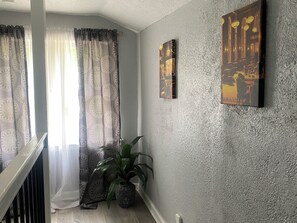 A room with a staircase, a potted plant, patterned curtains, and two wall-mounted paintings. - Jazzy Charmer Close To Everything KC Business Travel Space World Cup & More🏡 (Kansas City)
