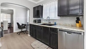 A modern kitchen with dark cabinets, a microwave, a sink, and a dishwasher.