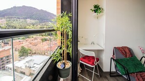 A balcony with a potted plant, a white desk chair, and a red cushion. - Downtown Bogotá | Work & Stay (Bogotá)