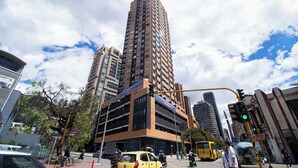 A tall urban building with multiple floors, surrounded by other high-rise buildings and a busy street with vehicles and pedestrians. - Downtown Bogotá | Work & Stay (Bogotá)