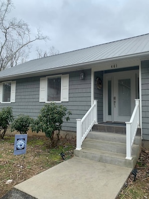 A two-story house with a front porch, a mailbox, and a small tree.