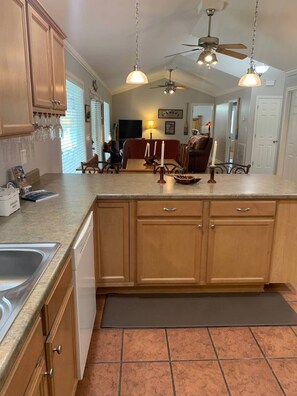 A kitchen with wooden cabinets, a countertop, a sink, and a ceiling fan.