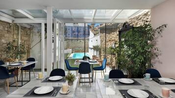 A dining area with tables set for four, a pool, and a view of a traditional courtyard.