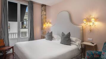 A hotel room with a large bed, checkered curtains, a stone accent wall, a decorative headboard, and wall-mounted lamps.