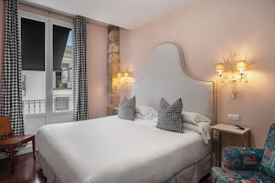 Habitación de hotel con una cama grande, cortinas a cuadros, una pared de acento de piedra, un cabecero decorativo y lámparas fijadas a la pared.