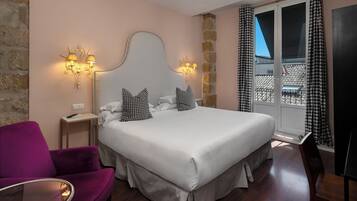 Habitación de hotel con cama, una silla, mesita de noche y ventana con cortinas.