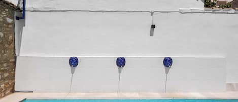A swimming pool with a white wall and blue fixtures.