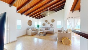 Amplia sala de estar con techo alto de madera, un conjunto de sofá, una mesa de centro y decoración en la pared.