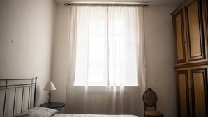 A bedroom with a bed, a nightstand, a chair, and a wardrobe.