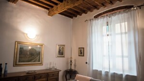 A cozy room with a wooden ceiling, a cushioned sofa, a wooden cabinet, and a window with sheer curtains.