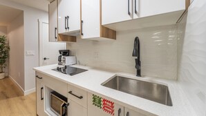A modern kitchen with white cabinets, a stainless steel sink, a black faucet, and a built-in oven.