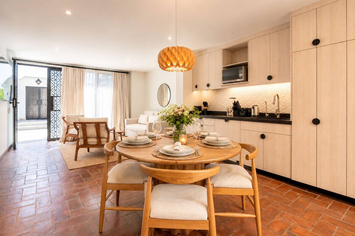 Une cuisine moderne avec des meubles en bois, une table à manger pour quatre personnes et une grande fenêtre.