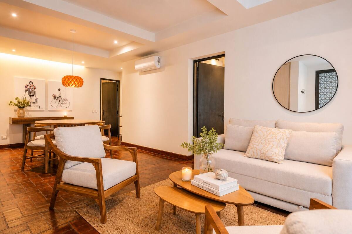 Un salon moderne comprenant un canapé, des fauteuils, une table basse et un coin repas avec une table et des chaises.