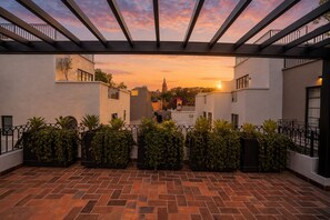 A courtyard with a brick floor, potted plants, and a pergola structure.