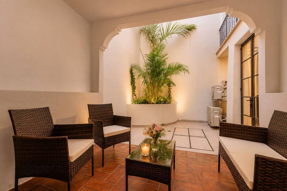 Un espace de détente intérieur, chaleureux, avec des meubles en osier, une table en verre et une plante en pot.
