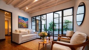 Una sala de estar con sofá, sillón, mesa de centro y una obra de arte en la pared.