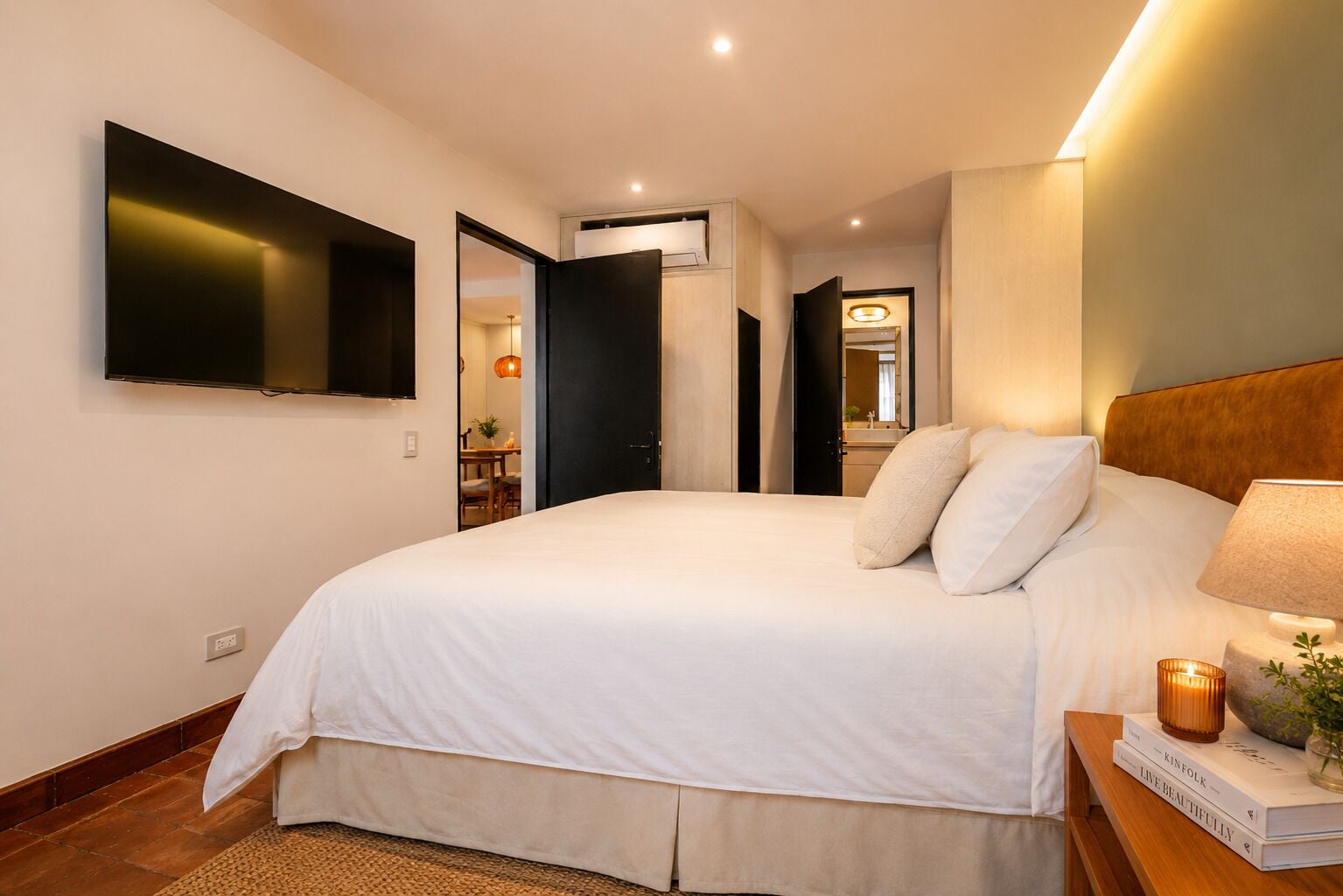 Une chambre à coucher comprenant un lit, une table de chevet, une lampe et un téléviseur fixé au mur.