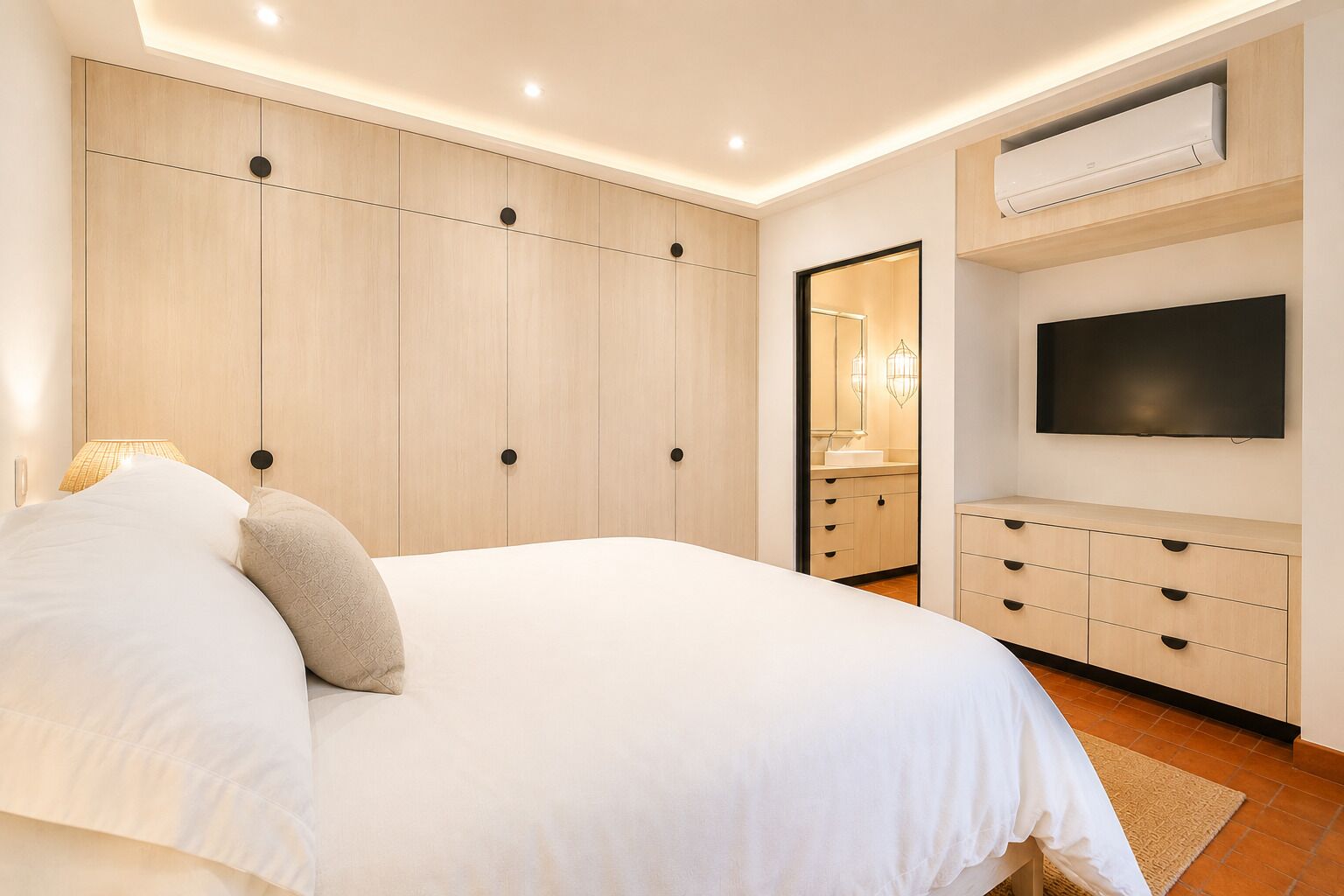 A bedroom with a bed, a TV, a wardrobe, and a mirror.