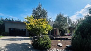 A landscaped outdoor area with a building, a paved driveway, and a variety of trees and shrubs.