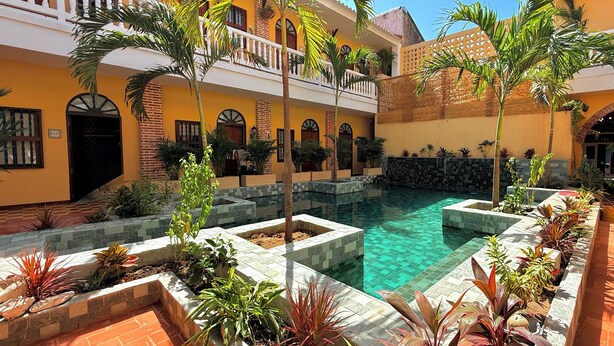 A courtyard with a pool, surrounded by buildings with balconies and arched windows.