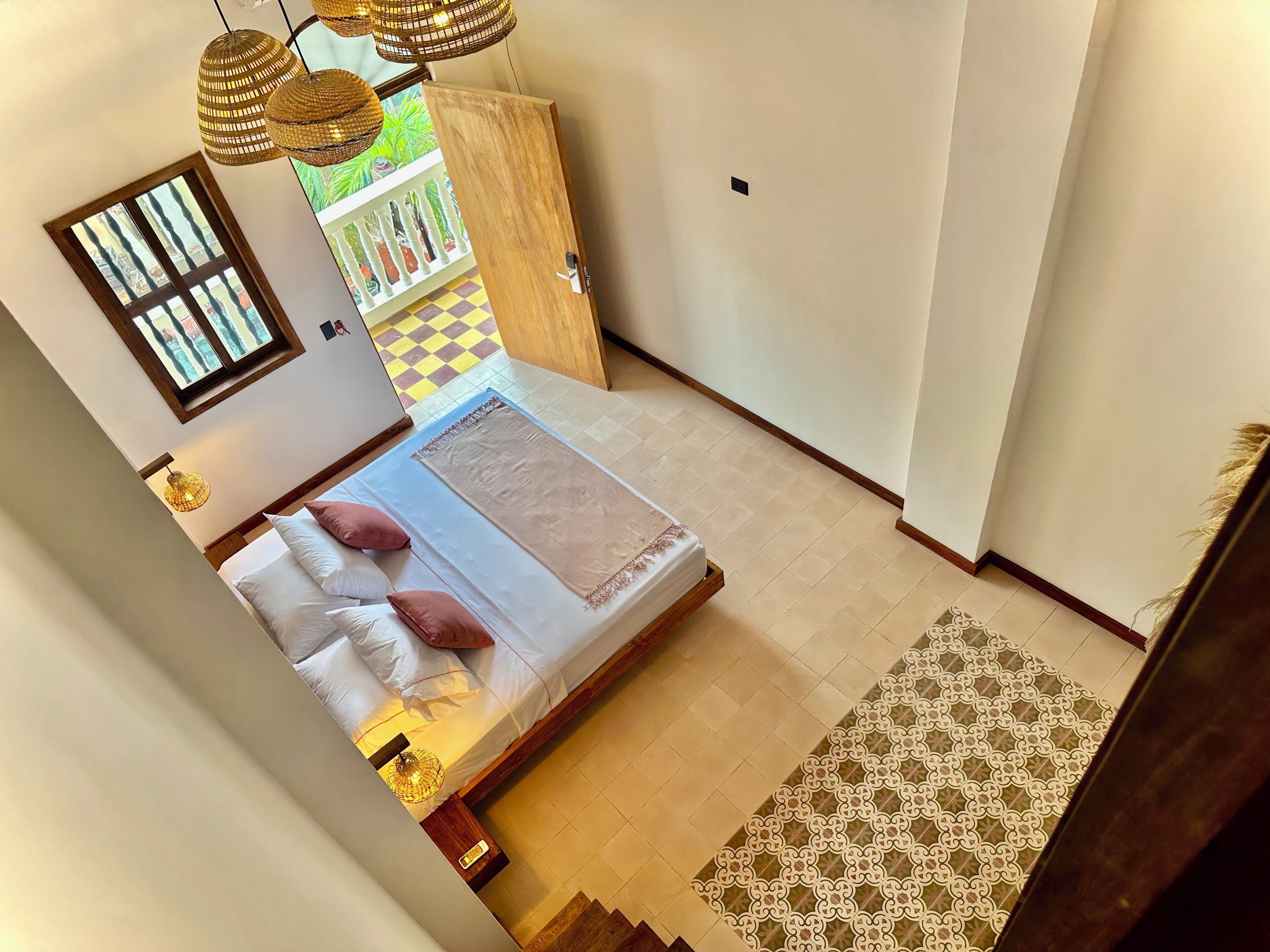 Ein Schlafzimmer mit Bett, Nachttischlampen, einem Fenster und Blick ins Freie.