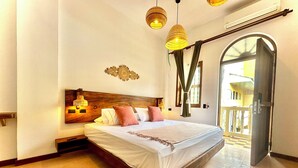 A spacious bedroom with a large bed, wooden headboard, and a view of the outside balcony.