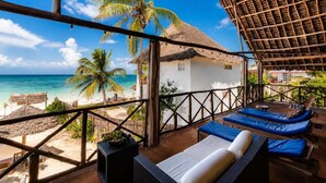 A beach view from a thatched-roof structure with lounge chairs and a small table. - Zanzibar beach escape  (Bwejuu)