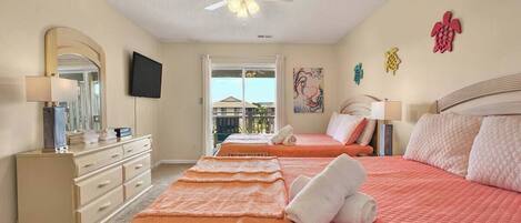 A bedroom with two beds, a ceiling fan, a TV, a dresser, and a window with a view.