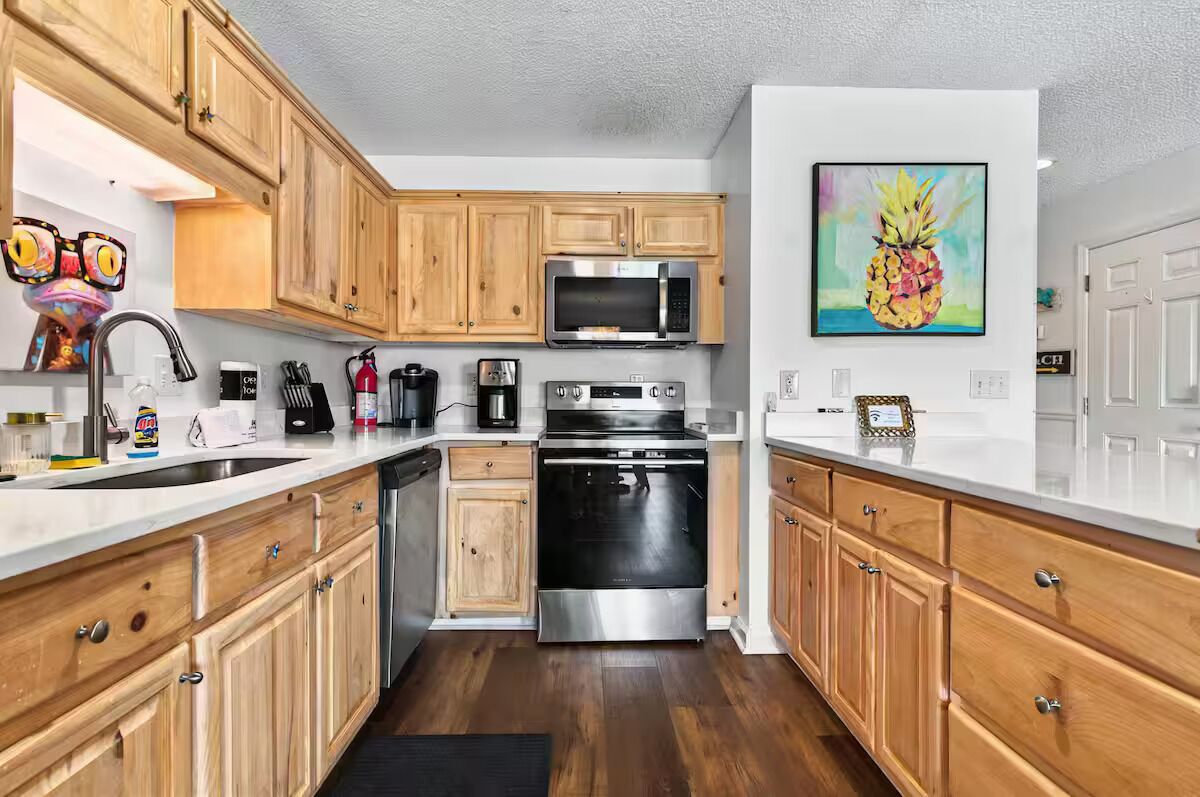 A kitchen with wooden cabinets, a stainless steel oven, a microwave, and a coffee maker.