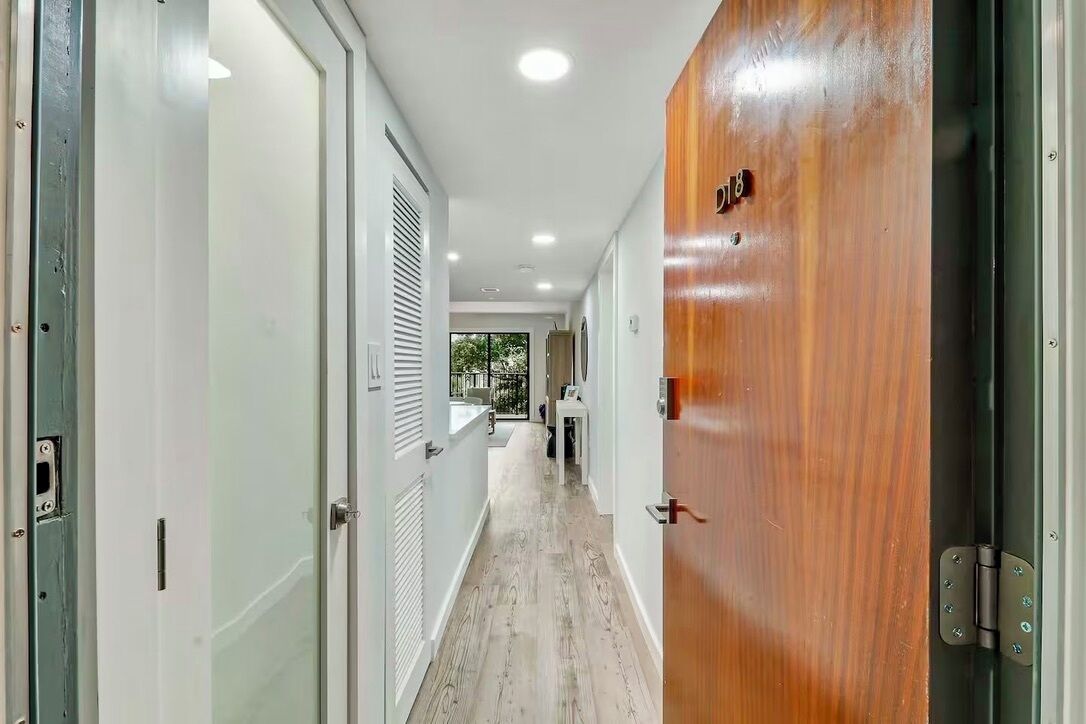 A hallway with a wooden door labeled "18", white walls, and a light-colored floor.