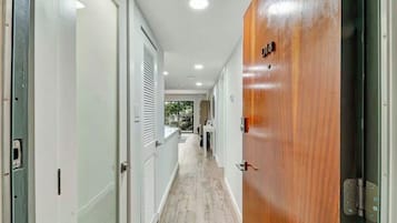 A hallway with a wooden door labeled "18", white walls, and a light-colored floor.