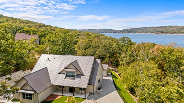 A two-story house with a sloped roof, a covered porch, and a view of a lake.