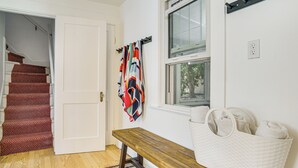 A hallway with a wooden bench, a colorful towel, a white basket, and a window with a view of trees. - 1 Mi to Beach: Home w/ Bocce Court in Cape Cod (West Yarmouth)