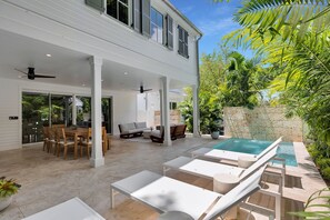 A spacious outdoor area with a pool, lounge chairs, and a dining area with a table and chairs.