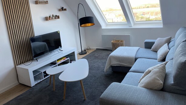 Un salon moderne avec un téléviseur, un canapé et une petite table.