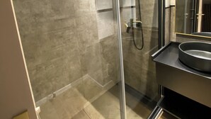 Une salle de bain moderne avec une douche à parois de verre, un lavabo et un miroir.
