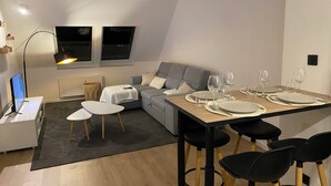 Un salon moderne comprenant un coin repas, un canapé gris, une table basse blanche et une table à manger pour quatre personnes.