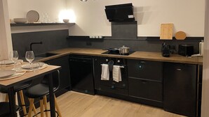 Une cuisine moderne avec des appareils électroménagers noirs, des plans de travail en bois et un coin repas équipé de tabourets.