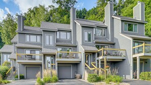 A multi-story residential building with a garage, balconies, and a landscaped front yard.