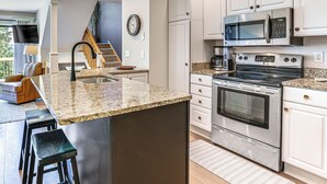 A modern kitchen with granite countertops, stainless steel appliances, and a central island with bar stools.