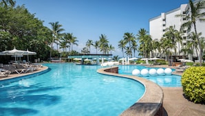 A resort pool with lounge chairs and umbrellas, surrounded by palm trees and a building. - Ocean Breeze Puerto Vallarta (Puerto Vallarta)